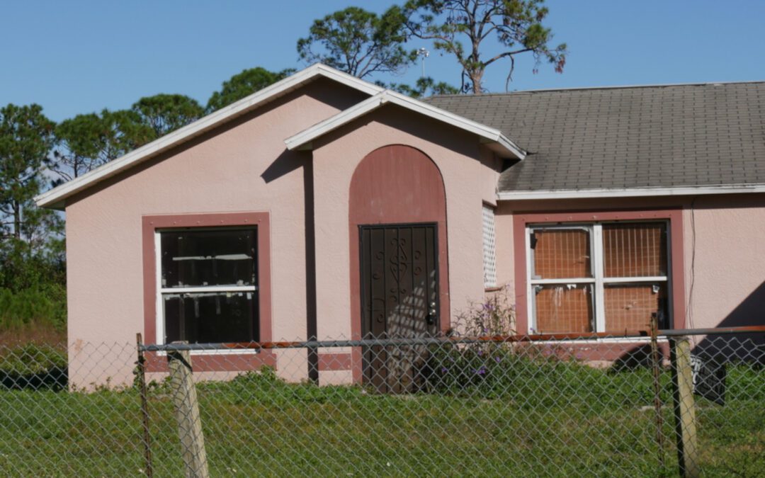 Small Pink House With A Chain Link Fence In Front Of It.